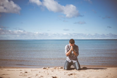 Daily Devotion - Faith Lutheran Church, Wesley Chapel, FL - Man praying on the beach